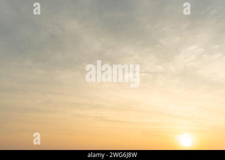 Die Sonne untergeht am Abend am Meer mit orangefarbenem Himmel und seltsamen Wolken wird als natürliche Hintergrundtextur in dekorativen Kunstwerken verwendet. Stockfoto