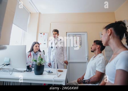Ein zuversichtlicher Arzt bespricht medizinische Ergebnisse mit einem Patienten Paar und bietet erfolgreiche Behandlungsmöglichkeiten in einer Klinik. Stockfoto