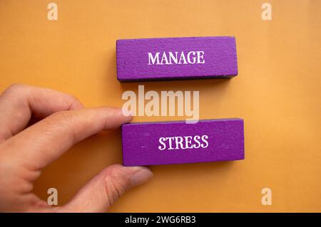 Verwalten Sie Stress-Schriften auf violetten Holzblöcken mit orangem Hintergrund. Konzeptionelles Symbol für psychische Gesundheit. Draufsicht, Kopierraum. Stockfoto