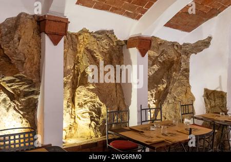 Das Innere eines Restaurants mit einer in den Felsen gehauenen Mauer, Castagneto Carducci, Livorno, Toskana, Italien Stockfoto