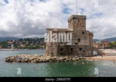 Die Burg am Meer, erbaut 1551, um die Stadt vor den Sarazenen Piraten zu schützen, mit Menschen, die sich sonnen und schwimmen, Rapallo, Genua, Ligurien, Italien Stockfoto