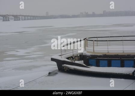 Schwimmendes Restaurant, Schiff am Ufer des Dnipro. Winter frostiges Wetter mit Schnee und gefrorenem Wasser. Stockfoto