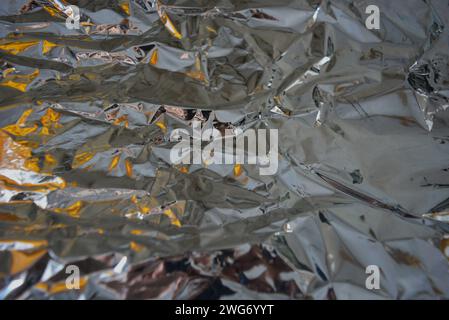 Stilvoller, grauer, reflektierender Melik-Hintergrund. Festlicher Hintergrund mit Helligkeit und Lichteffekten und Glanz auf silbernem zerknittertem Film. Stockfoto