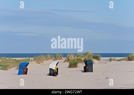 Liegestühle am Meer auf Borkum mit Windrädern im Hintergrund Stockfoto