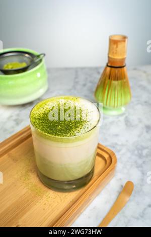 Eine Tasse grüner Matcha mit Pulver auf einem Holzbrett. Stockfoto