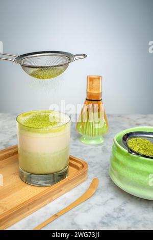 Eine Tasse grüner Matcha mit Pulver auf einem Holzbrett. Stockfoto