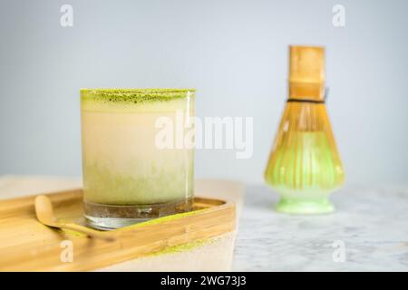 Eine Tasse grüner Matcha mit Pulver auf einem Holzbrett. Stockfoto