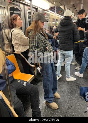 Teenager-Mädchen steckte sich in die Welt in ihrem Handy ein, während sie in Manhattan in New York City fährt Stockfoto