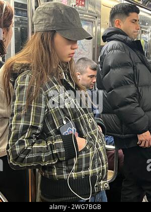 Teenager-Mädchen steckte sich in die Welt in ihrem Handy ein, während sie in Manhattan in New York City fährt Stockfoto