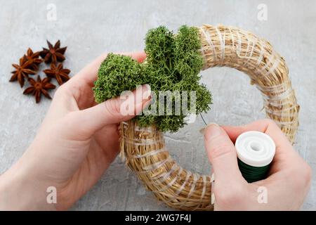 Blumengeschäft am Arbeitsplatz: Wie erstelle ich Weihnachten Tür-Kranz mit Moos und Hortensia Blumen trocknen. Schritt für Schritt Anleitung. Stockfoto