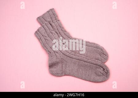 Pinke Stricksocken aus Wolle auf rosa Hintergrund Stockfoto