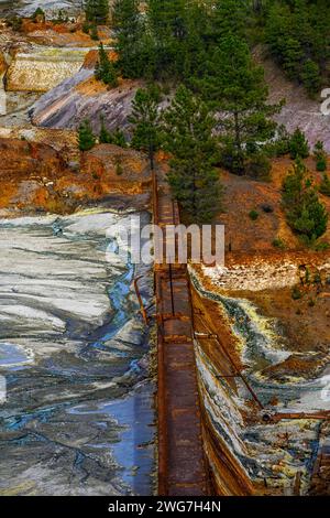 Die leuchtenden Orangetöne eines sauren Baches stehen im Kontrast zu einer Steinmauer im historischen Bergbaugebiet Rio Tinto Stockfoto