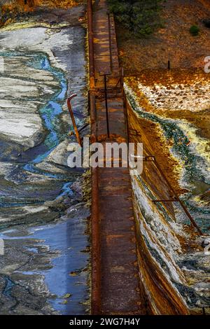 Die leuchtenden Orangetöne eines sauren Baches stehen im Kontrast zu einer Steinmauer im historischen Bergbaugebiet Rio Tinto Stockfoto