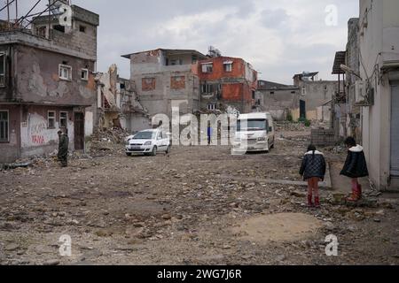 Hatay, Türkei. Februar 2024. Menschen laufen zwischen eingestürzten Gebäuden. Das größte Erdbeben in der Türkei erlebte die Türkei am 6. Dezember 2023 in der Grenzregion Syrien. Nach den aufeinanderfolgenden Erdbeben von 7,4 und 7,7 waren 10 Städte in der östlichen Region betroffen. Im Stadtzentrum von Hatay, einer der am stärksten betroffenen Städte, befinden sich noch immer Ruinen eingestürzter Gebäude. (Foto: Tunahan Turhan/SOPA Images/SIPA USA) Credit: SIPA USA/Alamy Live News Stockfoto