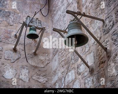 Zwei Bronzeglocken hängen an den Wänden in der historischen Kapelle St. Johannes der Evangelist in der Altstadt von Jerusalem. Stockfoto