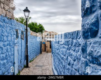 Zwischen zwei blauen Mauern schlängelt sich ein schmaler Fußweg im historischen Zentrum von Tzfat in Nord-Israel. Stockfoto