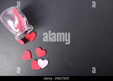 Herzen aus einer Flasche auf schwarzem Hintergrund. Valentinstag-Konzept. Stockfoto