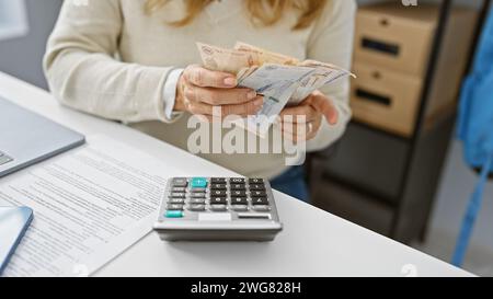 Hispanische Frau, die kolumbianische Pesos in einem modernen Büro hält. Stockfoto