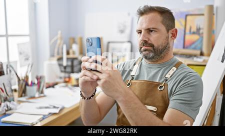 Gutaussehender reifer Mann mit grauen Haaren, der ein Selfie in einem Kunststudio macht. Stockfoto