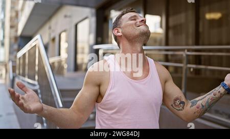 Fröhlich tätowierter Mann im Tank-Top kichert frei auf einem sonnigen Bürgersteig der Stadt und verkörpert den lässigen urbanen Lebensstil. Stockfoto