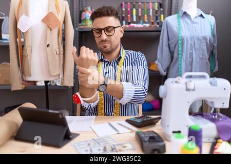 Hispanischer Mann mit Bartschneiderin Designer, der im Atelier arbeitet und Schmerzen an Händen und Fingern, Arthritis-Entzündung hat Stockfoto