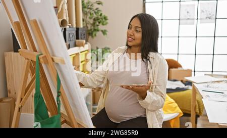 Selbstbewusster und lächelnder junger schwangerer Künstler zeichnet gern im Kunststudio Stockfoto