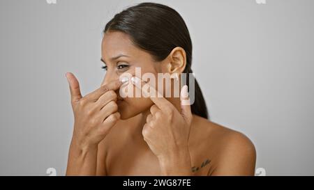 Junge lateinische Frau, die Pickel über isolierten weißen Hintergrund wirft Stockfoto