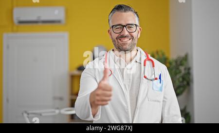 Ein grauhaariger Arzt, der in der Klinik Daumen hoch hält Stockfoto