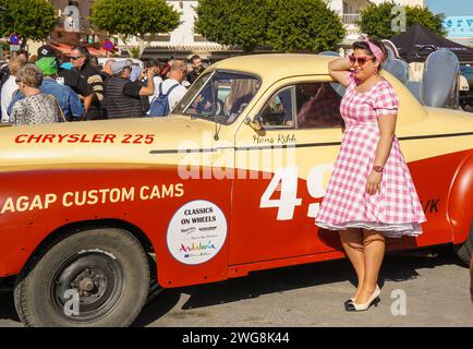 Eine Frau im Stil der 50er Jahre posierte vor einem alten Oldtimer beim Rockin Race Jamboree 2024, Rockabillies, Torremolinos, Andalusien, Spanien. Stockfoto