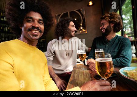 Fröhliches Porträt eines afroamerikanischen jungen Mannes mit einem Lächeln im Afro-Stil und Blick auf die Kamera. Stockfoto