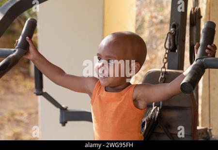 afroamerikaner, gemischtes Kleinkind, das draußen im Hof zu Hause in einem Fitnessgerät arbeitet Stockfoto