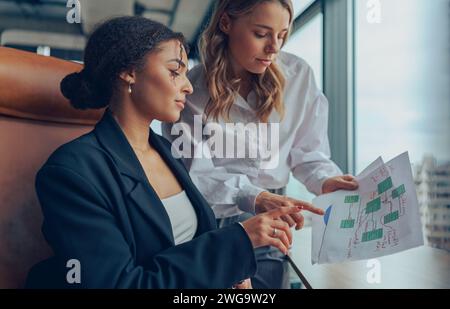 Zwei professionelle Führungskräfte, weibliche Experten, die über die Zusammenarbeit mit Finanzbuchhaltungsunterlagen diskutieren Stockfoto