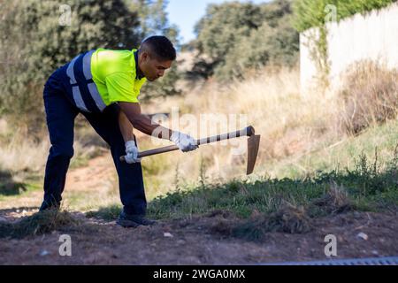 Porträt eines männlichen Latino-Gärtners in Arbeitskleidung, der im Boden gräbt Stockfoto