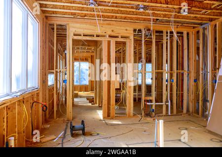 Der Arbeiter installiert elektrische Drähte, Isolierungen und Deckenleuchten vor Gipskartonplatten in einem neuen Haus Stockfoto