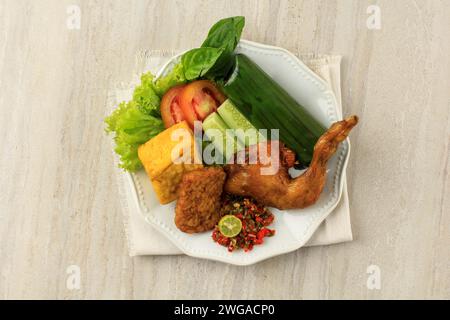 Top View Nasi Timbel Komplit, traditioneller sundanischer Reis mit Bananenblatt, serviert mit gebratenem Huhn, Tempeh, Tofu und Chilli-Paste Stockfoto