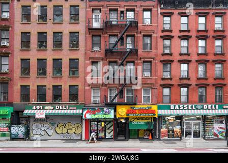 New York City altmodische Apartmenthäuser mit externen Feuerleitern und Geschäften im Erdgeschoss Stockfoto