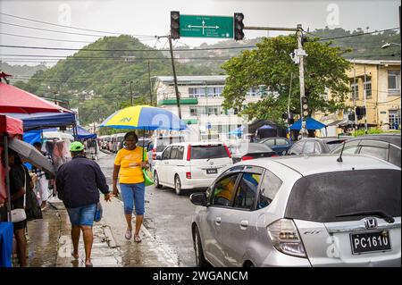 Eine Frau, die mit einem bunten Regenschirm an einem regnerischen Tag in der Innenstadt von Castries, St. Lucia, Januar 2024 läuft. Stockfoto