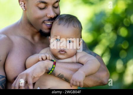 Multiethnische Eltern und stauntes Baby mit gemischter Rasse. Außenporträt für gemischte ethnische Familien. Birassisches multiethnisches Baby Kind. Wunderschön vielfältig Stockfoto