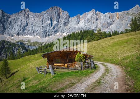 Tolle Wander- und Reiselage, ländliches Holzhaus am grünen Hang. Malerische Dachsteinberge im Hintergrund, Ramsau am Dachstein, Styri Stockfoto