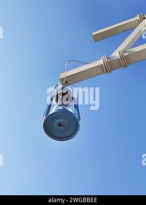 Altmodische antike blaue Farbe Öl- oder Gaslampe oder Laterne hängt vom Holzbalken gegen blauen Himmel, Metall Retro Licht Vintage Lampe, mit Kopie sp Stockfoto