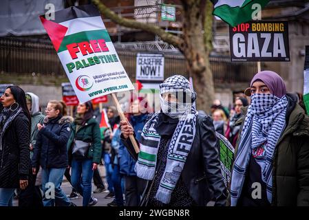 London, Großbritannien. Februar 2024. Demonstranten halten Plakate während des Nationalmarsches für Palästina: Waffenstillstand jetzt! Die palästinensische Solidaritätskampagne organisierte einen marsch für Palästina, um einen Waffenstillstand zu erzielen und den Völkermord in Gaza zu stoppen. Israel hat bei seinem brutalen Angriff auf Gaza über 25.000 Palästinenser getötet, und Tausende weitere befinden sich unter den Trümmern. Quelle: SOPA Images Limited/Alamy Live News Stockfoto