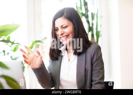 Geschäftsfrau sitzt vor einem Laptop und lacht Stockfoto