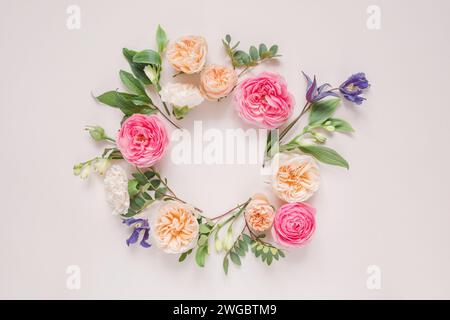 Blick von oben auf ein kreisförmiges Blumenarrangement aus Rosen, Chrysanthemen, Alstroemeria-Blumen und Laub auf rosa Hintergrund Stockfoto