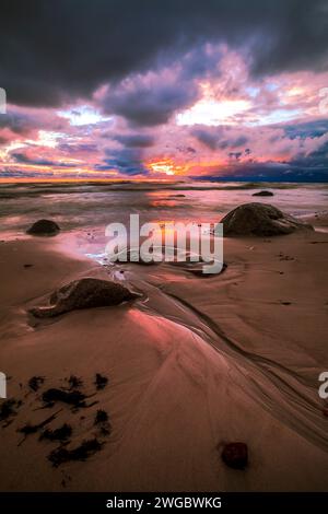 Stürmischer Sonnenuntergang über Felsen an einem Ostseestrand, Litauen Stockfoto