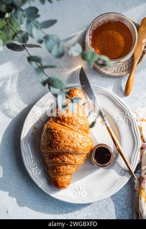 Blick von oben auf ein frisch gebackenes Croissant mit Schokoladenhonig und einer Tasse Tee Stockfoto