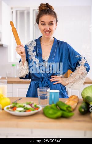 Hausfrau in einem Hausmantel mit einer Nadel in den Händen in der Küche Stockfoto