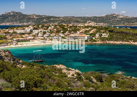 Farbenfrohe Landschaft mit Blick auf Baia Sardinia Stadt, Cala Batistoni Strand und Bucht mit verankertem Schooner und umliegende Landschaft, Baia Sardinia, Sardinien, Stockfoto