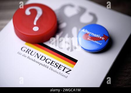 Parteianstecker der AfD und Fragezeichen auf dem deutschen Grundgesetz, Symbolfoto für die AfD-Verbotsdebatte *** AfD-Parteiabzeichen und Fragezeichen zur deutschen Verfassung, symbolisches Foto für die AfD-Verbotsdebatte Stockfoto