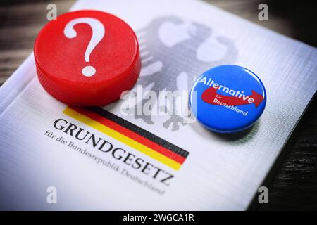 Parteianstecker der AfD und Fragezeichen auf dem deutschen Grundgesetz, Symbolfoto für die AfD-Verbotsdebatte *** AfD-Parteiabzeichen und Fragezeichen zur deutschen Verfassung, symbolisches Foto für die AfD-Verbotsdebatte Stockfoto