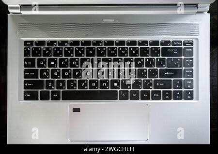 Flache, schwarze Tastatur eng-Thai auf grauem, modernem Laptop mit Touchpad Stockfoto